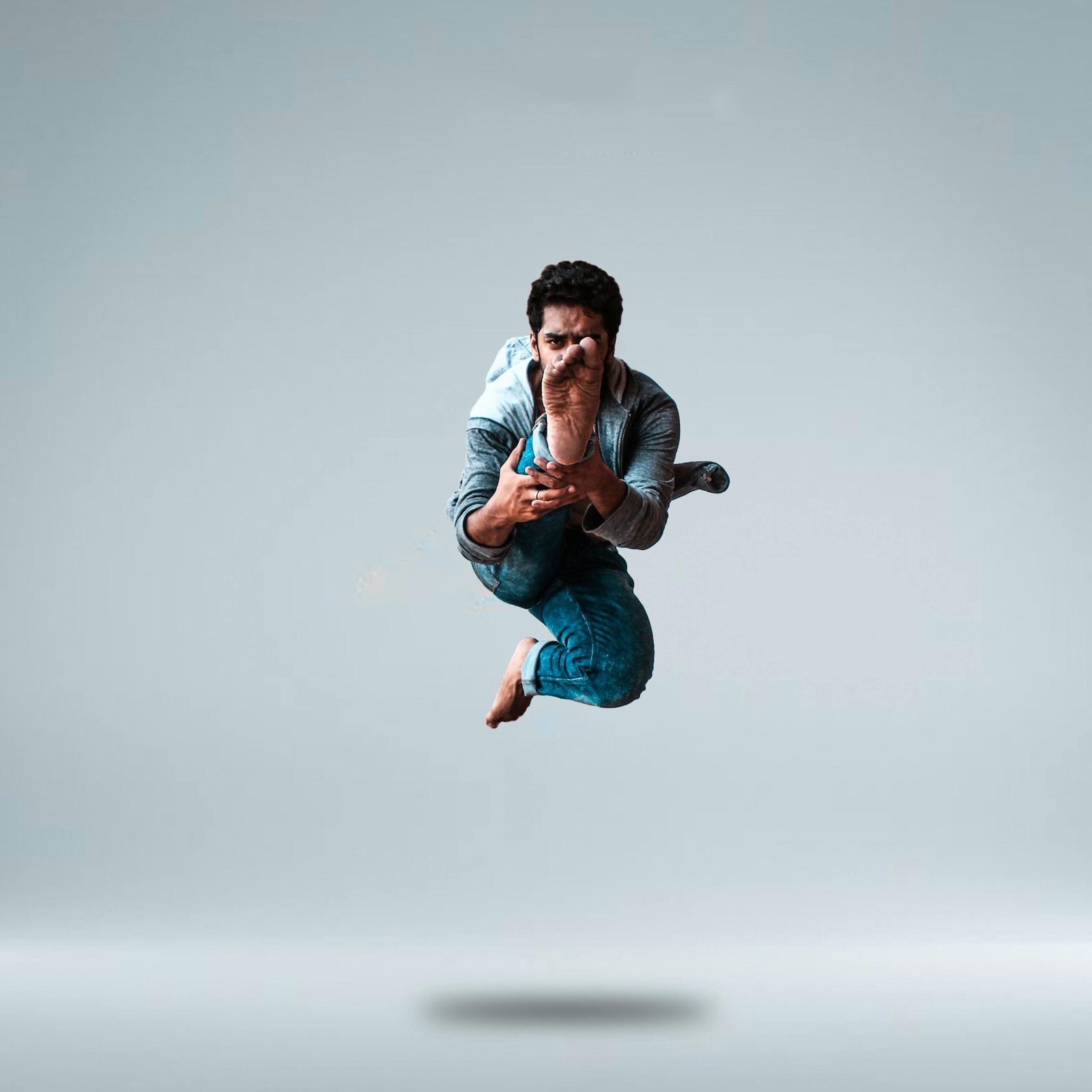 A skillful male dancer performs an impressive mid-air stretch, showcasing athleticism and agility.